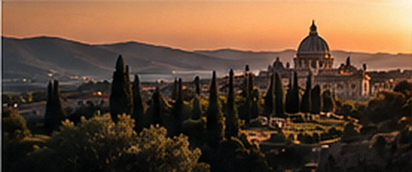 Cypress trees and hills at sunset with the dome of St Peter's in the distance